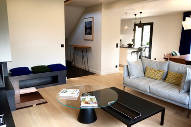 Idée de décoration pour un salon design de taille moyenne et ouvert avec un mur blanc, parquet clair, une cheminée d'angle, un téléviseur fixé au mur et un sol beige.