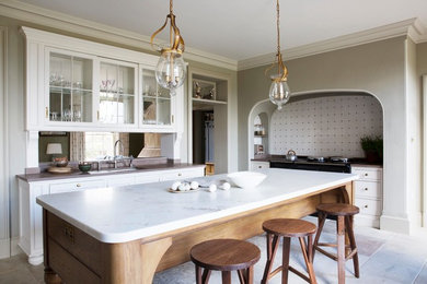 This is an example of a large traditional galley eat-in kitchen in London with a single-bowl sink, raised-panel cabinets, white cabinets, marble benchtops, panelled appliances, limestone floors, with island and beige floor.