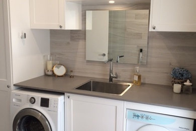 Photo of a small modern single-wall utility room in Sydney with a drop-in sink, recessed-panel cabinets, white cabinets, quartz benchtops, grey walls, porcelain floors and a side-by-side washer and dryer.