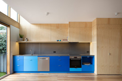 This is an example of a medium sized contemporary single-wall open plan kitchen in Melbourne with a built-in sink, flat-panel cabinets, blue cabinets, composite countertops, grey splashback, stone slab splashback, stainless steel appliances, medium hardwood flooring, no island and grey worktops.
