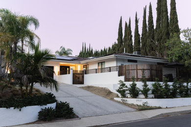 Inspiration for a mid-sized 1950s white one-story stucco exterior home remodel in Los Angeles with a green roof and a gray roof