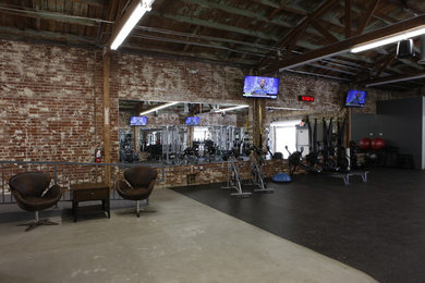 Multifunktionaler, Mittelgroßer Industrial Fitnessraum mit brauner Wandfarbe, Betonboden und grauem Boden in Los Angeles