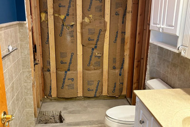 Example of a mid-sized classic beige tile and porcelain tile porcelain tile, beige floor and single-sink bathroom design in Chicago with raised-panel cabinets, white cabinets, a two-piece toilet, blue walls, an integrated sink, solid surface countertops and a built-in vanity