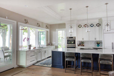 Large beach style u-shaped porcelain tile, beige floor and coffered ceiling eat-in kitchen photo in Milwaukee with an undermount sink, flat-panel cabinets, blue cabinets, quartz countertops, white backsplash, porcelain backsplash, stainless steel appliances, an island and white countertops
