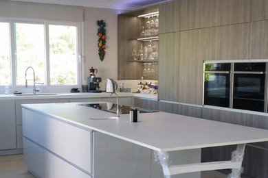 Photo of a mid-sized modern u-shaped eat-in kitchen in Malaga with an undermount sink, flat-panel cabinets, medium wood cabinets, black appliances, ceramic floors and with island.