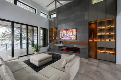 Example of a large minimalist open concept porcelain tile, beige floor and wood wall living room design in Charlotte with a two-sided fireplace, a stone fireplace and a media wall