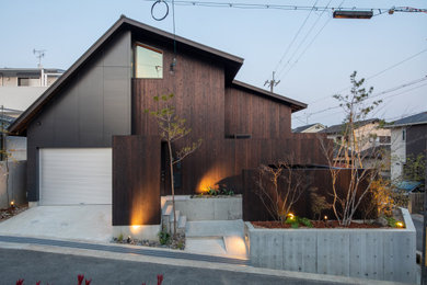 Photo of a large modern two-storey brown house exterior in Kyoto with wood siding, a gable roof, a metal roof and a black roof.