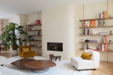 Idées déco pour un salon contemporain avec un mur beige, un sol en bois brun, une cheminée standard et un sol marron.