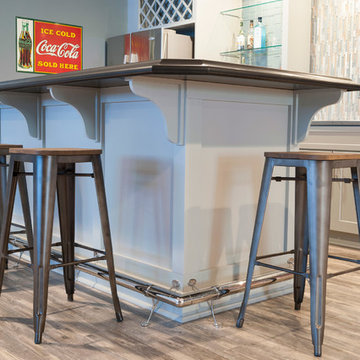 Basement Bar with Gray Island, Corian Countertops, and a Foot Rail