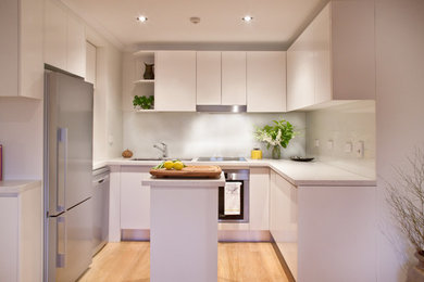 Design ideas for a small contemporary u-shaped eat-in kitchen in Sydney with a double-bowl sink, white cabinets, wood benchtops, glass sheet splashback and with island.