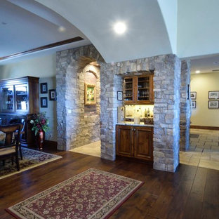 他の地域のトランジショナルスタイルのおしゃれなウェットバー (アンダーカウンターシンク、レイズドパネル扉のキャビネット、中間色木目調キャビネット、御影石カウンター、マルチカラーのキッチンパネル、ライムストーンの床、トラバーチンの床、マルチカラーのキッチンカウンター) の写真
