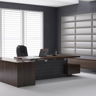 This is an example of a modern home office and library in New York with grey walls and a freestanding desk.