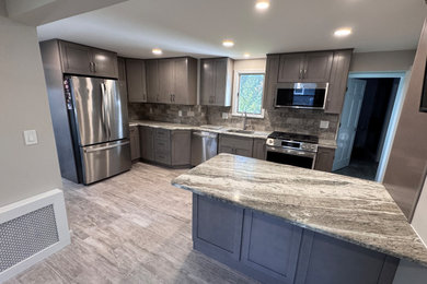 Example of a large minimalist porcelain tile and gray floor kitchen design in Newark with an undermount sink, shaker cabinets, gray cabinets, granite countertops and an island