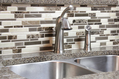 Example of a small classic u-shaped eat-in kitchen design in Austin with recessed-panel cabinets, light wood cabinets, quartz countertops, brown backsplash, glass tile backsplash, black appliances and no island
