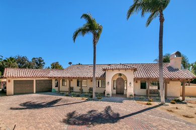 Large southwestern beige one-story stucco exterior home idea in San Diego with a tile roof