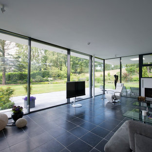 Photo of a large modern formal open plan living room in Frankfurt with brown walls, terracotta flooring, a wood burning stove, a metal fireplace surround, a freestanding tv and beige floors.