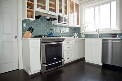 Design ideas for a mid-sized traditional u-shaped separate kitchen in San Francisco with an undermount sink, glass-front cabinets, white cabinets, quartz benchtops, blue splashback, glass tile splashback, stainless steel appliances, no island, cork floors, brown floor and grey benchtop.