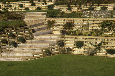 Design ideas for a mid-sized modern full sun hillside retaining wall landscape in Kansas City for summer.