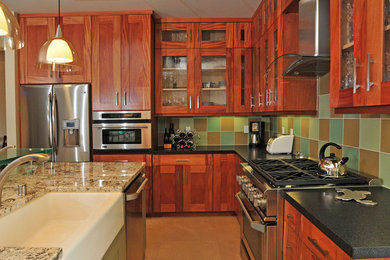 Inspiration for a kitchen remodel in San Diego with glass-front cabinets, medium tone wood cabinets, granite countertops, green backsplash and stainless steel appliances
