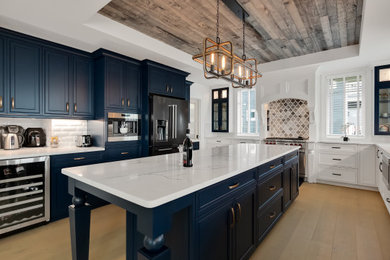 Inspiration for a large contemporary u-shaped eat-in kitchen remodel in Detroit with a farmhouse sink, raised-panel cabinets, blue cabinets, marble countertops, white backsplash, subway tile backsplash, stainless steel appliances, an island and white countertops