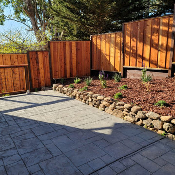 Backyard Patio with River Rock Retaining Wall and Privacy Fence