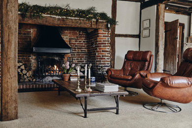 Inspiration for a large rustic formal open plan living room in Surrey with beige walls, carpet, a standard fireplace, a brick fireplace surround, beige floors, exposed beams and all types of wall treatment.