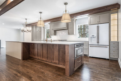 Photo of a transitional kitchen in Chicago with shaker cabinets, grey cabinets, quartz benchtops, white splashback, medium hardwood floors, with island, brown floor and white benchtop.