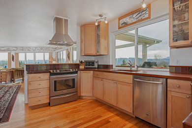 Inspiration for a large contemporary u-shaped medium tone wood floor eat-in kitchen remodel in Other with an undermount sink, glass-front cabinets, light wood cabinets, wood countertops, multicolored backsplash, glass tile backsplash, stainless steel appliances and an island