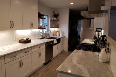 Inspiration for a mid-sized modern galley gray floor and ceramic tile eat-in kitchen remodel in Dallas with a farmhouse sink, shaker cabinets, white cabinets, marble countertops, white backsplash, stainless steel appliances, gray countertops and porcelain backsplash
