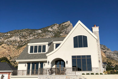 Exemple d'une façade de maison blanche chic en stuc à un étage avec un toit à deux pans, un toit en shingle et un toit gris.
