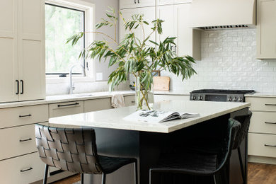 Mid-sized transitional u-shaped medium tone wood floor and brown floor eat-in kitchen photo in Other with an undermount sink, shaker cabinets, white cabinets, quartz countertops, white backsplash, subway tile backsplash, black appliances, an island and white countertops