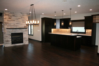 Example of a mid-sized transitional l-shaped dark wood floor and brown floor open concept kitchen design in Other with an undermount sink, shaker cabinets, black cabinets, quartz countertops, beige backsplash, porcelain backsplash, stainless steel appliances and an island