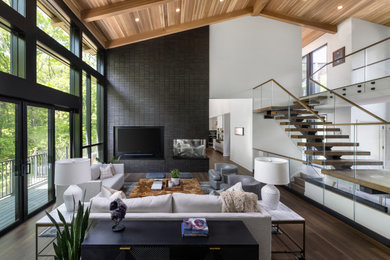 Living room - huge modern formal and open concept dark wood floor, brown floor and wood ceiling living room idea in Detroit with white walls, a two-sided fireplace, a brick fireplace and a wall-mounted tv