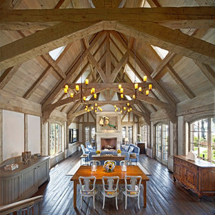 Example of a huge country dark wood floor and brown floor dining room design in Other with gray walls and a stone fireplace