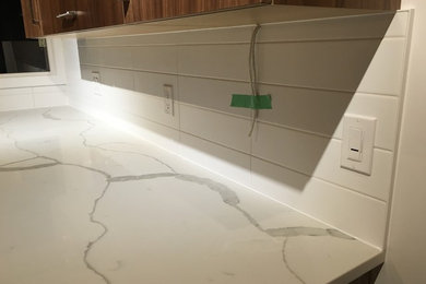 Mid-sized minimalist u-shaped ceramic tile eat-in kitchen photo in Toronto with an undermount sink, flat-panel cabinets, medium tone wood cabinets, quartz countertops, white backsplash, ceramic backsplash, stainless steel appliances and a peninsula