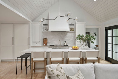 Large elegant light wood floor and brown floor kitchen photo in Boston with an undermount sink, shaker cabinets, white cabinets, quartz countertops, gray backsplash, quartz backsplash, paneled appliances, an island and gray countertops