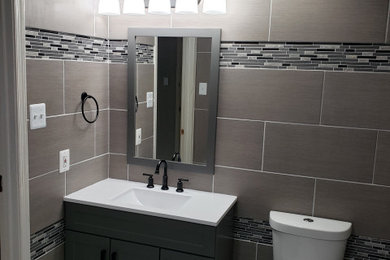Example of a huge trendy master gray tile and porcelain tile porcelain tile, gray floor and single-sink bathroom design in Baltimore with raised-panel cabinets, gray cabinets, a two-piece toilet, gray walls, an undermount sink, quartz countertops, white countertops, a niche and a freestanding vanity