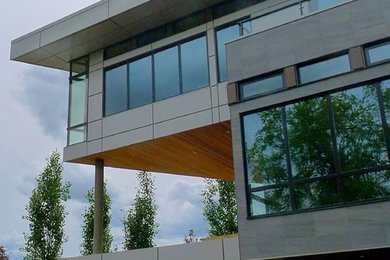 This is an example of a large contemporary three-storey grey exterior in Edmonton with mixed siding and a flat roof.