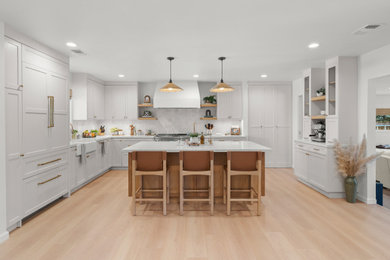 Inspiration for a mid-sized scandinavian beige floor kitchen remodel in Los Angeles with a farmhouse sink, shaker cabinets, quartz countertops, white backsplash, ceramic backsplash, stainless steel appliances and white countertops
