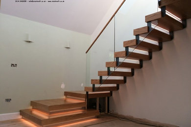 Inspiration for a contemporary wood l-shaped staircase in Buckinghamshire with open risers and glass railing.