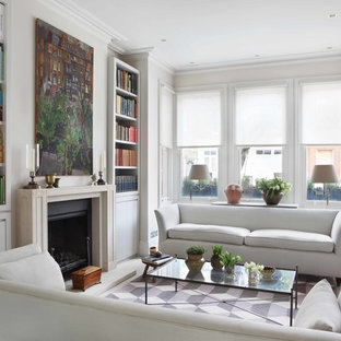 Inspiration för ett mellanstort funkis separat vardagsrum, med ett bibliotek, vita väggar, ljust trägolv, en standard öppen spis och en spiselkrans i betong