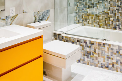 Inspiration for a mid-sized contemporary bathroom in New York with yellow cabinets, a drop-in tub, flat-panel cabinets, a shower/bathtub combo, a one-piece toilet, a sliding shower screen and an integrated sink.