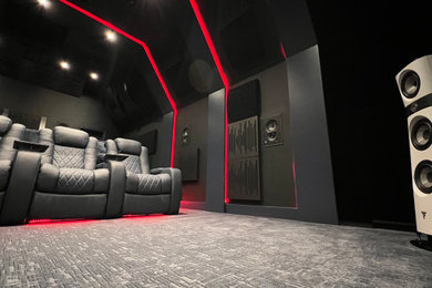 Foto de cine en casa cerrado minimalista grande con paredes negras, moqueta, pantalla de proyección y suelo gris
