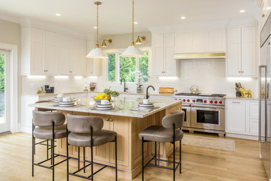 Example of a large transitional u-shaped light wood floor and brown floor eat-in kitchen design in New York with an undermount sink, recessed-panel cabinets, white cabinets, granite countertops, white backsplash, subway tile backsplash, stainless steel appliances, an island and white countertops