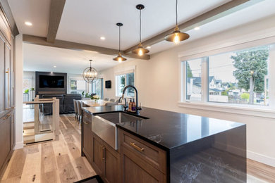 Example of a large mountain style light wood floor, brown floor and coffered ceiling eat-in kitchen design in New York with an undermount sink, shaker cabinets, brown cabinets, quartzite countertops, white backsplash, porcelain backsplash, stainless steel appliances, an island and black countertops