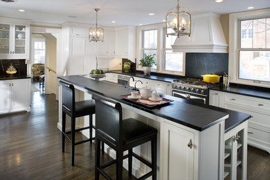 Photo of a large traditional l-shaped kitchen in Minneapolis with recessed-panel cabinets, white cabinets, soapstone benchtops, black splashback, stone slab splashback, black appliances, dark hardwood floors and with island.