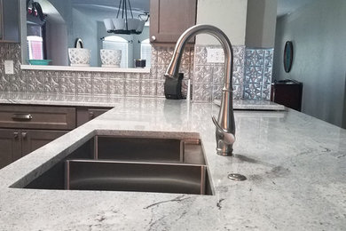 Mid-sized trendy u-shaped gray floor eat-in kitchen photo in Dallas with an undermount sink, shaker cabinets, gray cabinets, granite countertops, metallic backsplash, metal backsplash, stainless steel appliances, a peninsula and gray countertops