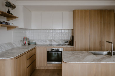 Inspiration for a mid-sized modern kitchen in Other with a single-bowl sink, light wood cabinets, marble benchtops, light hardwood floors and with island.