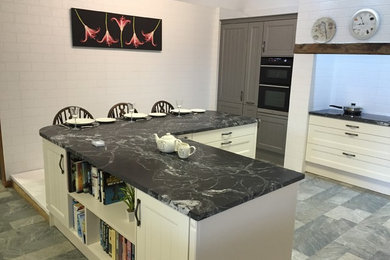 Design ideas for a medium sized modern l-shaped kitchen/diner in Other with white cabinets, granite worktops, white appliances, laminate floors, a breakfast bar, multi-coloured floors and multicoloured worktops.
