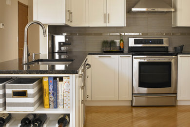Eat-in kitchen - small transitional u-shaped light wood floor eat-in kitchen idea in Calgary with shaker cabinets, white cabinets, granite countertops, porcelain backsplash, stainless steel appliances, a peninsula, a double-bowl sink and gray backsplash